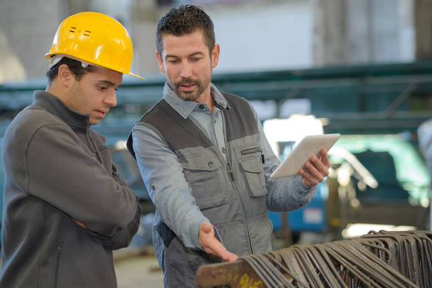 male supervisor with worker discussing over factory products - Foto, afbeelding