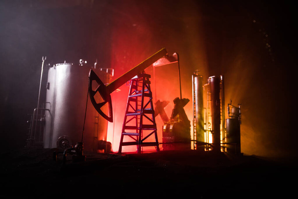 Διακόσμηση έργων τέχνης. Πετρελαϊκή αντλία και πετρελαϊκή εξέδρα ενέργειας βιομηχανικές μηχανές πετρελαίου τη νύχτα με ομίχλη και backlight. Εργοστάσιο διύλισης πετρελαίου. Ενεργειακή βιομηχανική έννοια. Επιλεκτική εστίαση - Φωτογραφία, εικόνα