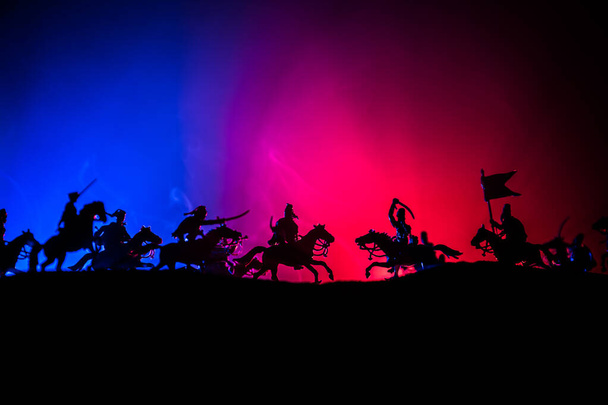 Scena di battaglia medievale con cavalleria e fanteria. Silhouette di figure come oggetti separati, lotta tra guerrieri su sfondo nebbioso dai toni scuri. Scena notturna
. - Foto, immagini