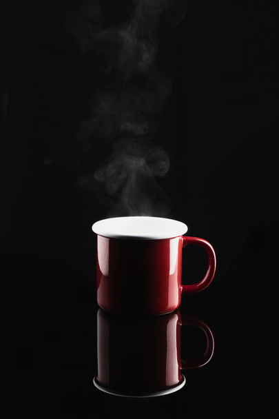 steaming coffee or tea in red mug with reflection on dark backgr - Fotoğraf, Görsel