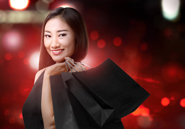 Asian woman holding black shopping bags with blurred lights back - Photo, Image