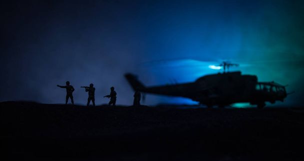 軍用ヘリコプター紛争地帯からを飛行する準備ができてのシルエット。霧のトーン バックライト付きの砂漠で始まるヘリコプター飾られて夜の映像。選択と集中. - 写真・画像