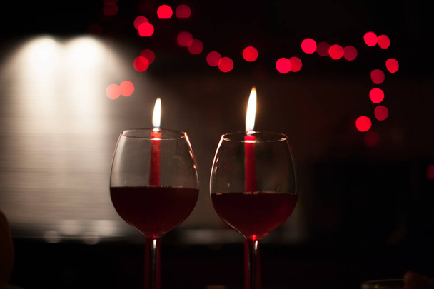 Romantyczna kolacja: dwa kieliszki wina i świece są w ciemności z nowego roku światła w tle - Zdjęcie, obraz