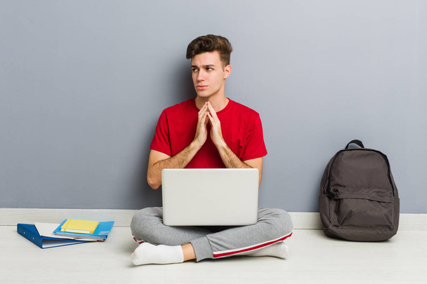 Jeune homme étudiant assis sur le sol de sa maison tenant un ordinateur portable
 - Photo, image