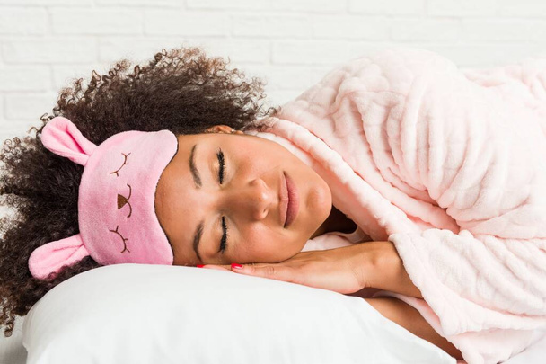 Νεαρή αφρικανική Αμερικανίδα γυναίκα που κοιμάται με ένα μαξιλάρι στο κρεβάτι - Φωτογραφία, εικόνα