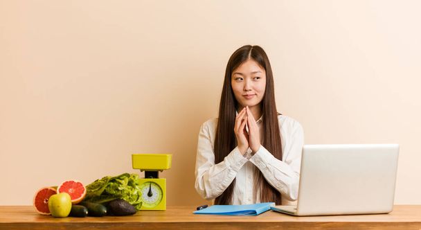 Jovem nutricionista chinesa que trabalha com seu laptop fazendo plano em mente, estabelecendo uma ideia
. - Foto, Imagem