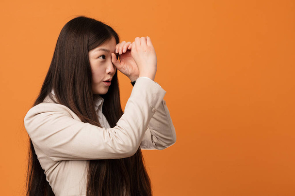Giovane donna cinese di affari guardando lontano tenendolo mano sulla fronte
. - Foto, immagini
