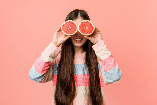 Young asian woman playing with a grapefruit - Valokuva, kuva