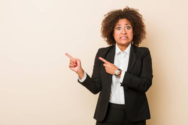 Jovem empresária afro-americana chocada apontando com os dedos indicadores para um espaço de cópia
. - Foto, Imagem