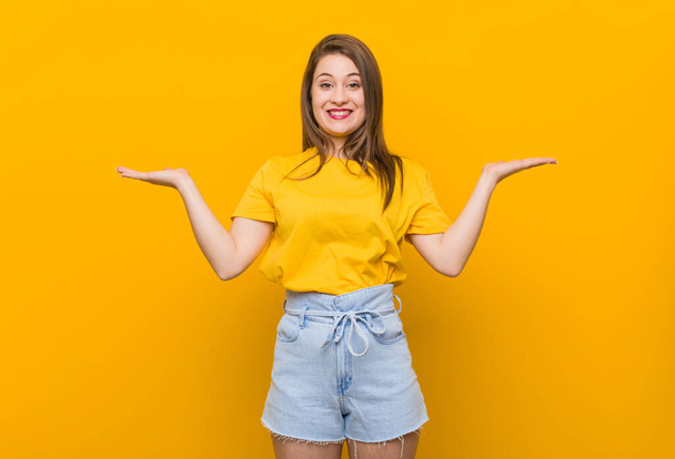 Młoda kobieta nastolatka w żółtej koszuli sprawia, że waga z ramionami, czuje się szczęśliwy i pewny siebie. - Zdjęcie, obraz