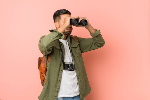 Young south-asian man looking through a binoculars. - 写真・画像