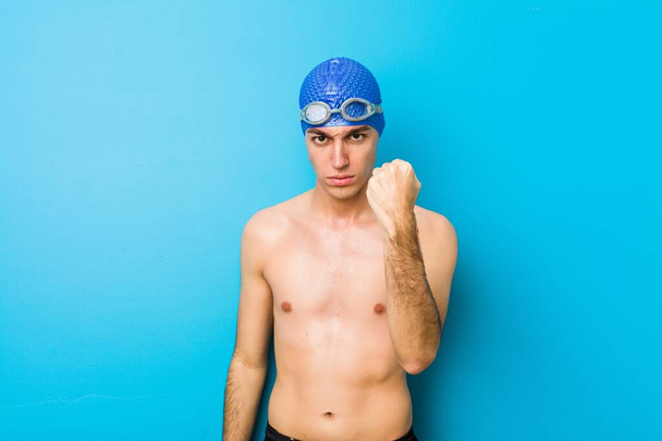 Fiatal úszó férfi ököllel a kamerának, agresszív arckifejezés. - Fotó, kép