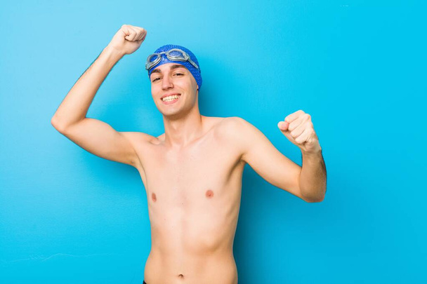 Νεαρός κολυμβητής γιορτάζει μια ξεχωριστή μέρα, πηδάει και σηκώνει τα χέρια με ενέργεια. - Φωτογραφία, εικόνα