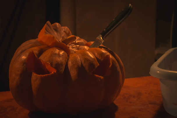 Halloween unfinished pumpkin with knife in itself  - Foto, Imagen