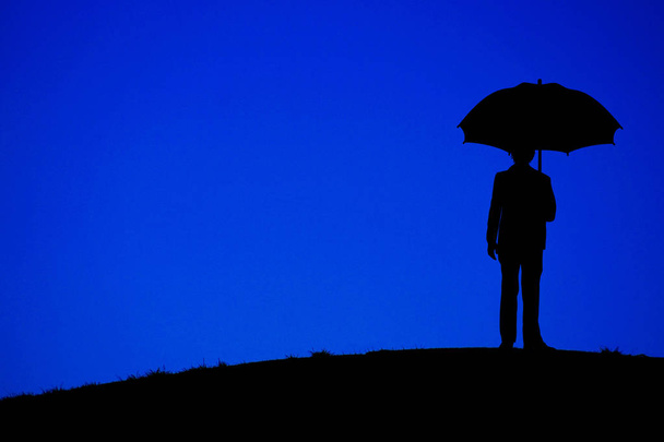 Hombre sosteniendo un paraguas de pie en la noche de las colinas
 - Foto, Imagen