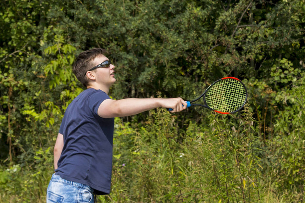Teen boy with a racket in hand plays badminton - Foto, imagen