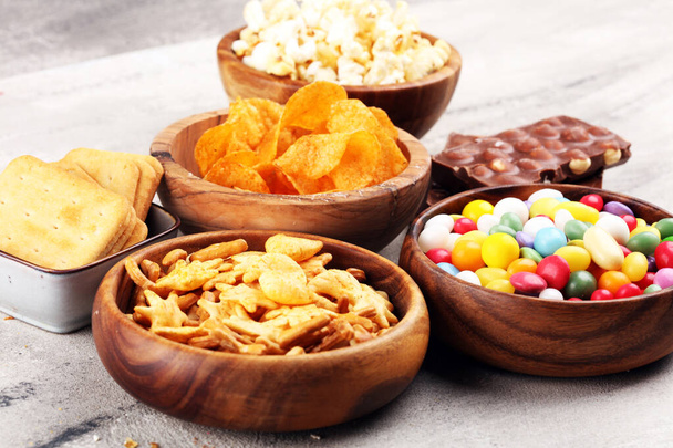 Salty snacks. Pretzels, chips, crackers in wooden bowls and cand - Photo, Image