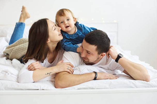 onnellinen perhe äiti isä ja lapsi jouluaamuna sängyssä
 - Valokuva, kuva