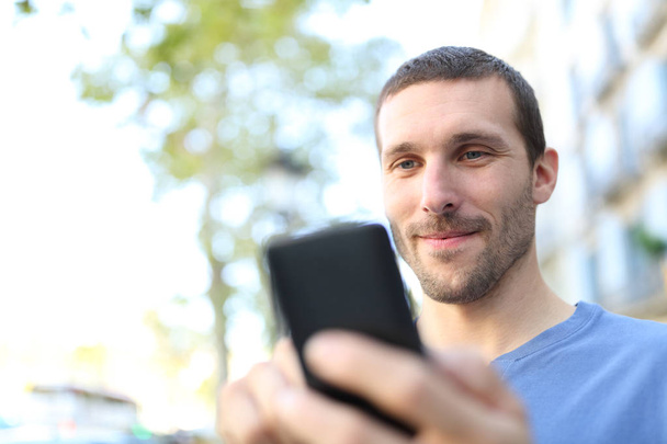 Closeup of a man using smart phone in the street - Foto, afbeelding