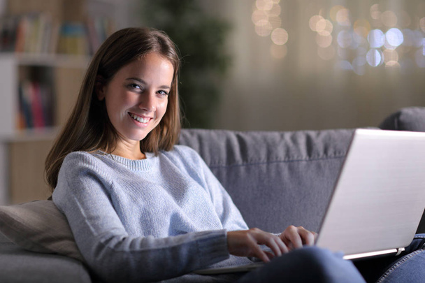 Happy woman using laptop looking at camera at home - Фото, изображение