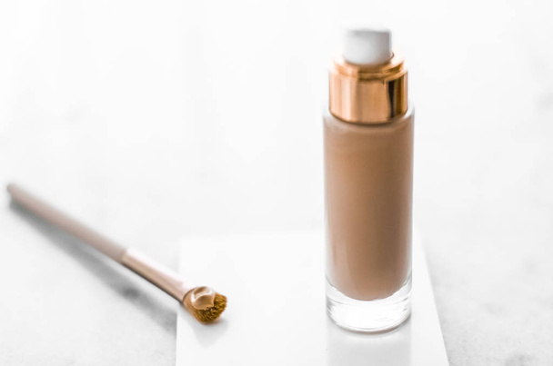 Бутылка для макияжа и контурная щетка на мраморе, макияж
 - Фото, изображение