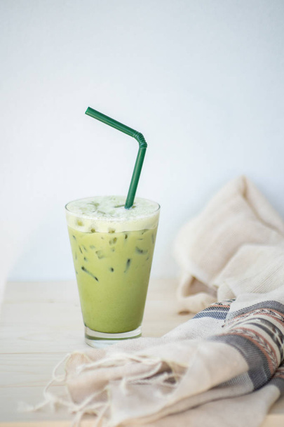 Thé vert glacé ou latte matcha sur grands verres avec paille sur table en bois blanc et objet de décoration de vêtements
. - Photo, image