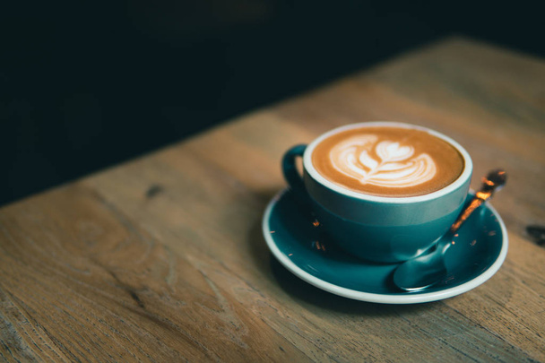 Καφές με καφέ latte art σερβίρεται σε ξύλινο τραπέζι. - Φωτογραφία, εικόνα