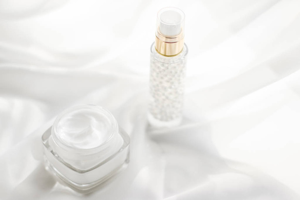 Gezicht crème moisturizer pot en serum gel op witte zijde, huid auto - Foto, afbeelding