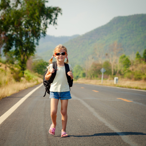 little girl with backpack walking on the road - Фото, изображение