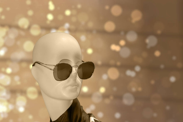 Schaufensterpuppe Kopf in Sonnenbrille, gedämpfte Farbe beige braun Hintergrund Bokeh Glanz - Foto, Bild