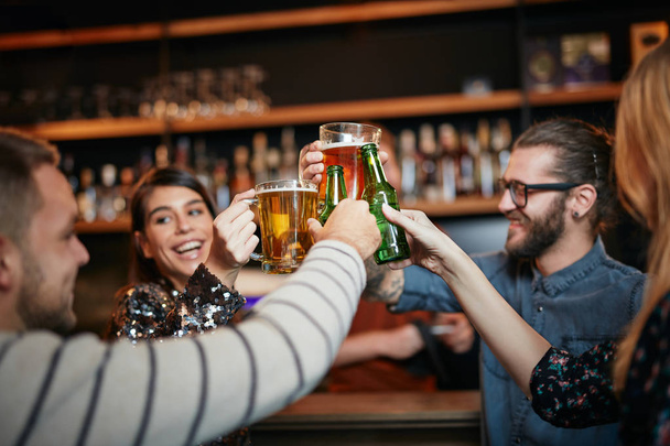 Друзья, стоящие в баре и пьющие пиво
. - Фото, изображение