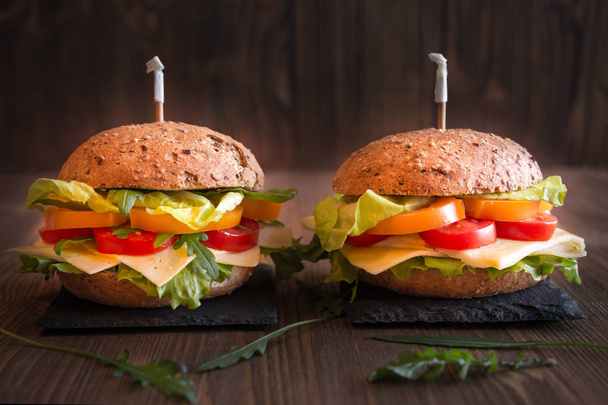 Delicious sandwiches with cheese, lettuce, vegetables and arugola on dark background - Foto, Bild