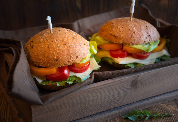 Вкусные сэндвичи с сыром, салатом, овощами и аруголой на тёмном фоне
 - Фото, изображение