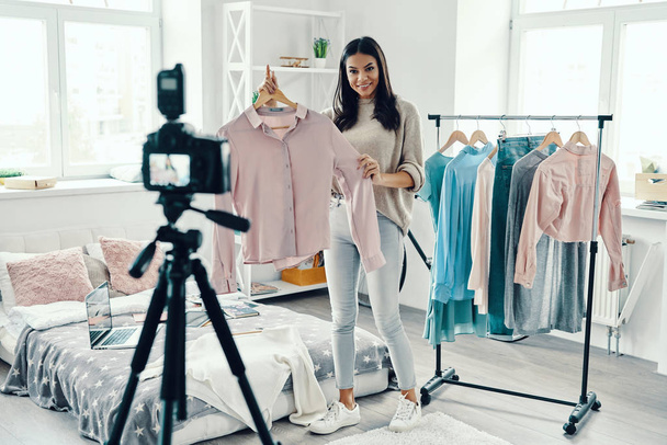 Beautiful young woman in casual clothing making social media video on camera and showing clothes  - Foto, Imagem