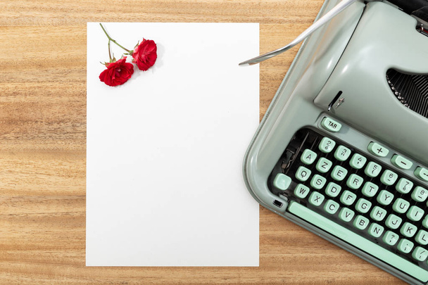 Стол с чистой бумагой, пишущей машинкой ретро и красными розами
 - Фото, изображение