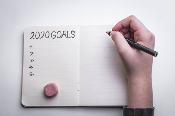 2020-as újévi cél, terv, cselekvési szöveg női kezű jegyzettömbön. - Fotó, kép