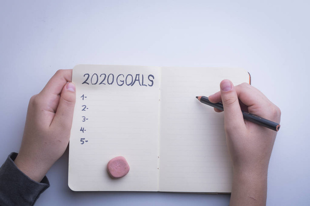 2020 nouvel an objectif, plan, texte d'action sur bloc-notes avec les mains de la femme
. - Photo, image