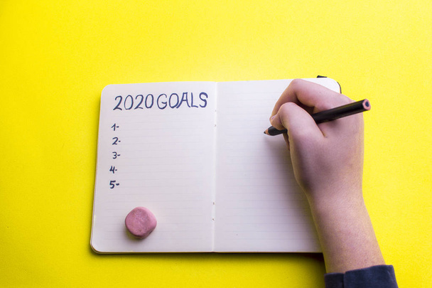 2020 año nuevo objetivo, plan, texto de acción en bloc de notas con las manos de la mujer
. - Foto, Imagen