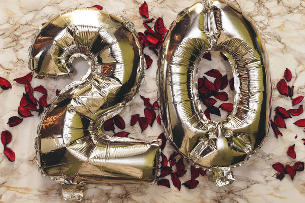 Zahl 20 zwanzig in Form von silbernen Luftballons auf Marmorgrund mit trockenen Blütenblättern verziert. Glückwunschkarte. Alles Gute zum Geburtstag Ballon Banner. Weihnachtsdekoration. - Foto, Bild