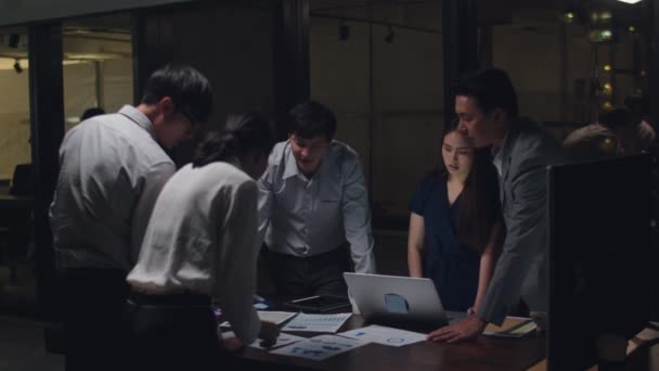 Millennial Asia business men and business women meeting brainstorming ideas about new paperwork project colleagues working together planning success strategy enjoy teamwork in small modern night office. - Séquence, vidéo