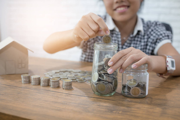 お金と財政の概念を保存,閉じる手の女の子の手は、電卓で計算とジュグガラスにコインを置きます.  - 写真・画像