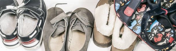 παιδικά παπούτσια αποθηκευμένα σε ένα τσαγκάρη μέσα σε μια ντουλάπα και σε διαφορετικές εποχές του χρόνου - Φωτογραφία, εικόνα