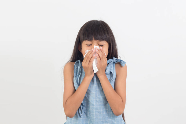 sick little girl blowing her nose isolated on white background - 写真・画像