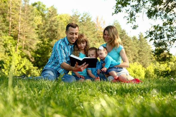 счастливая семья, читающая Библию на природе
 - Фото, изображение