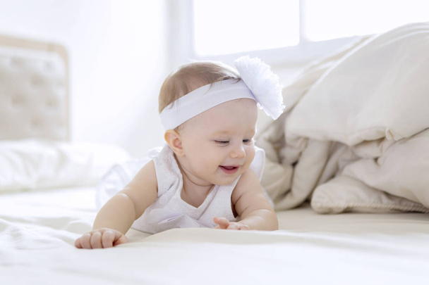 Χαριτωμένο κοριτσάκι που φοράει λευκό φόρεμα στο κρεβάτι - Φωτογραφία, εικόνα