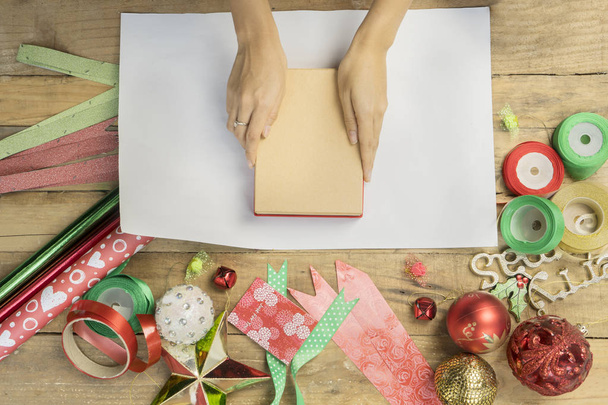 Female hands prepare to wrap a Christmas gift - Valokuva, kuva