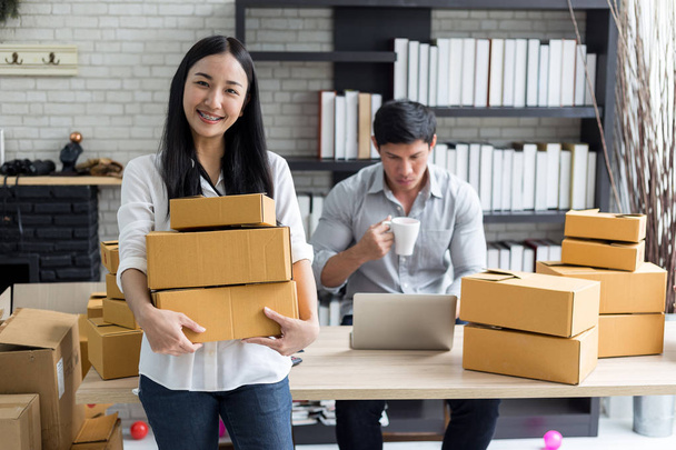 Portrait of smiling asian young woman with cardboard boxes standing in house office,startup Online Marketing concept - Fotó, kép