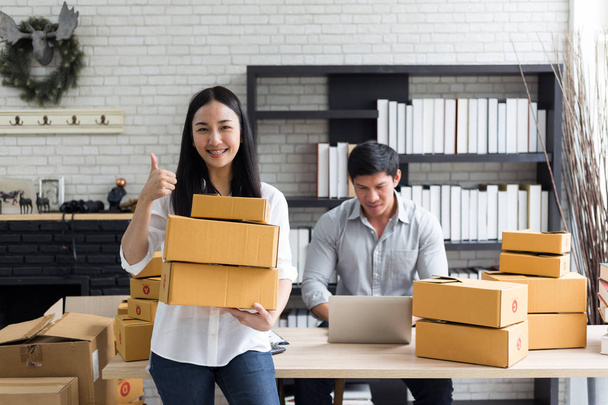 Portrait of smiling asian young woman with cardboard boxes standing in house office,startup Online Marketing concept - Фото, изображение