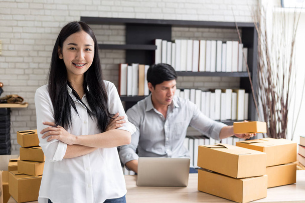 Портрет улыбающейся азиатской молодой женщины с картонными коробками, стоящими в домашнем офисе, стартап Концепция онлайн-маркетинга
 - Фото, изображение