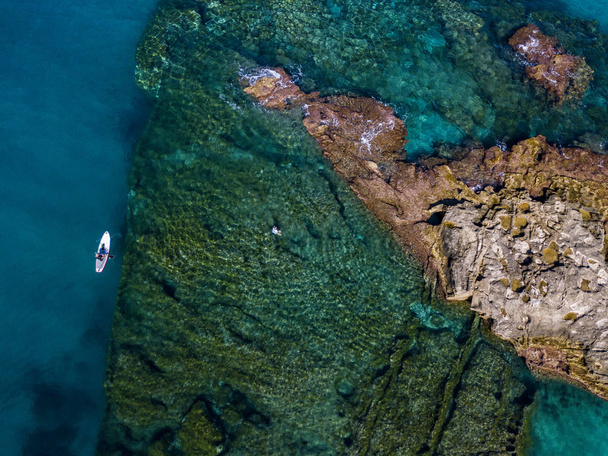 Vista aérea de una tabla de paddle en el agua flotando en un mar transparente, snorkel. Bañistas en el mar. Tropea, Calabria, Italia. Buceo relajación y vacaciones de verano. Costas, playas y rocas italianas
 - Foto, imagen